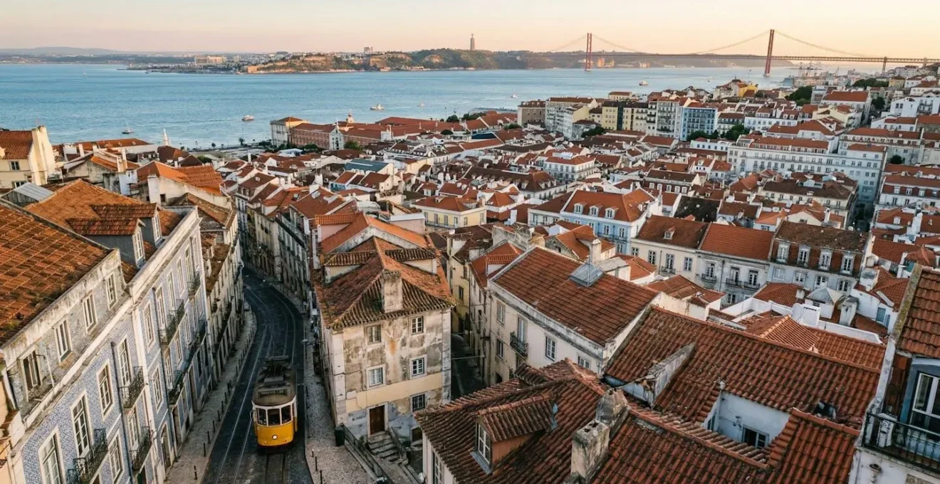 Vue panoramique de Lisbonne avec ses ruelles pavées et ses tramways jaunes sur fond de collines et du Tage au coucher du soleil