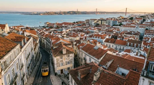 Vue panoramique de Lisbonne avec ses ruelles pavées et ses tramways jaunes sur fond de collines et du Tage au coucher du soleil