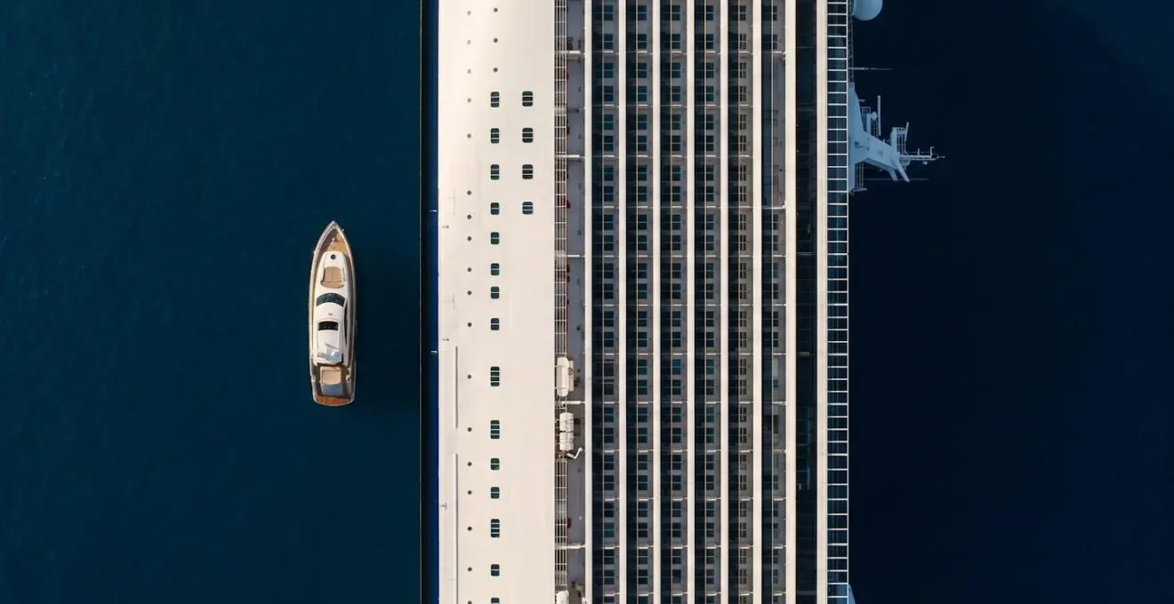 Vue aérienne comparant un méga-paquebot et un yacht de luxe côte à côte en mer