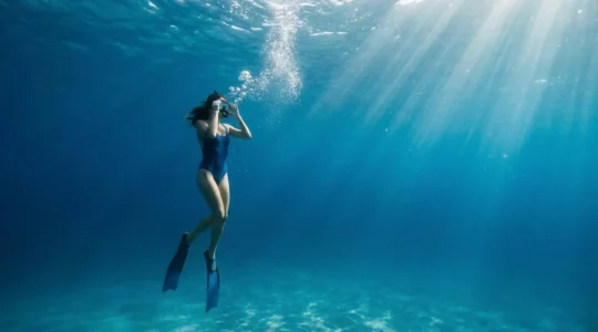 Plongeur en train d'ajuster son masque de snorkeling sous l'eau avec des bulles d'air visibles
